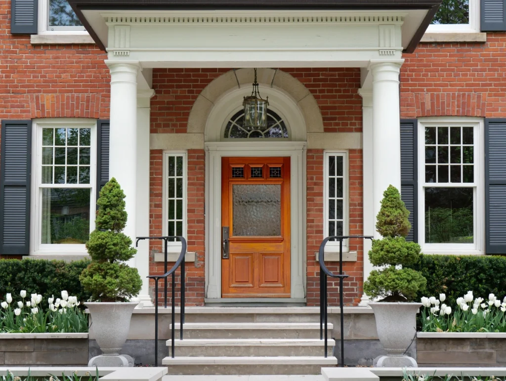 beautiful portico with white pillars in front of a home's brick exterior