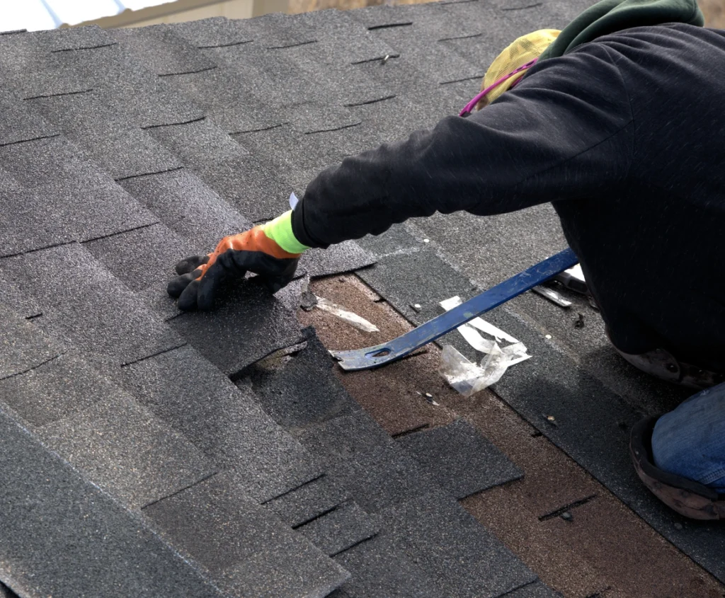 roofer using a pry bar to remove shingles