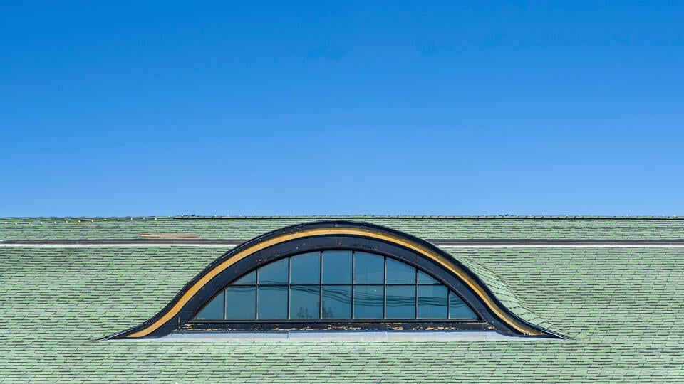 types of dormers-eyebrow curved dormer on green shingle roof