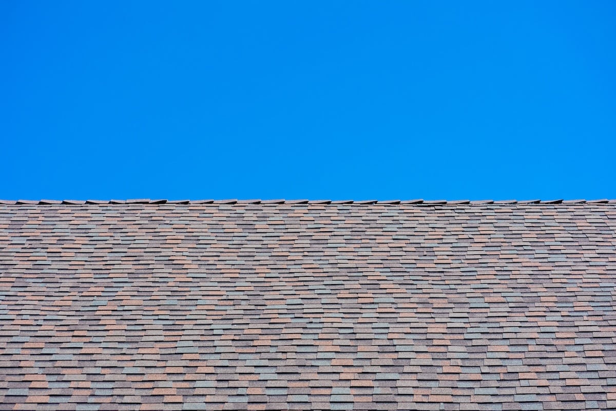 Laminated architectural roof shingles of different shapes and sizes give the rooftop dimensional appearance