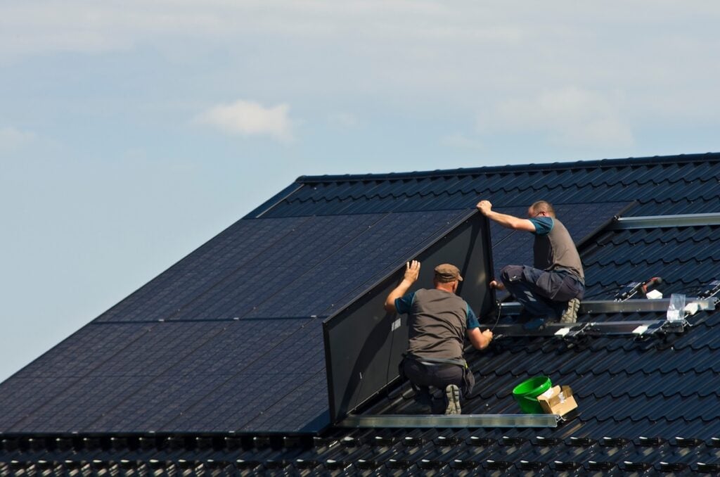 Installing new black solar panels on the metal roof