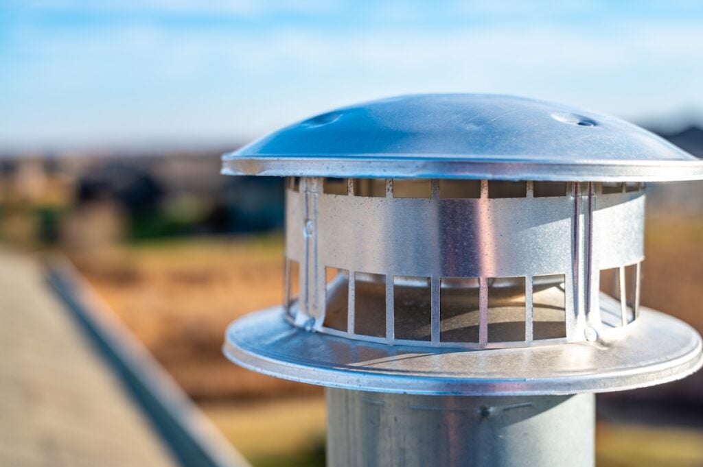 Typical rooftop chimney with a steel rain cap and shielding