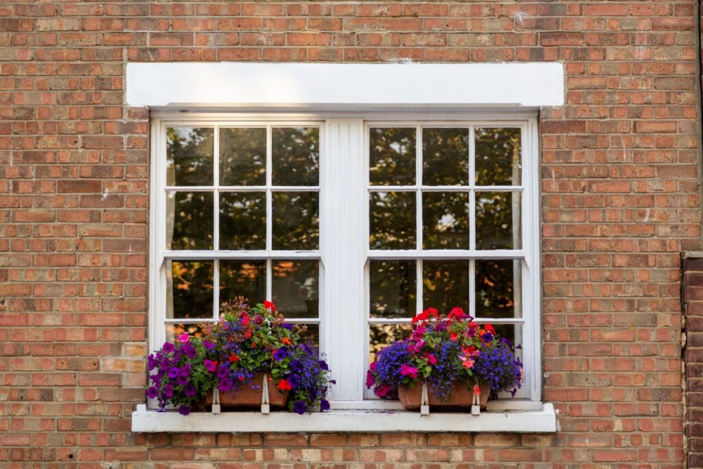 brick house with white windows and flowers