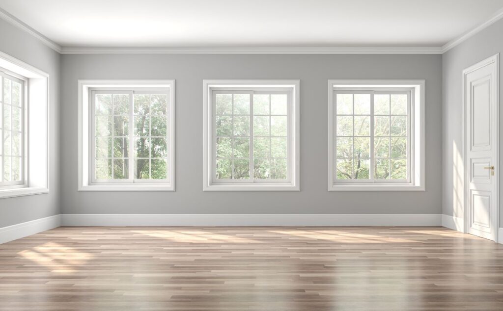 empty grey living room with large white windows facing a forest