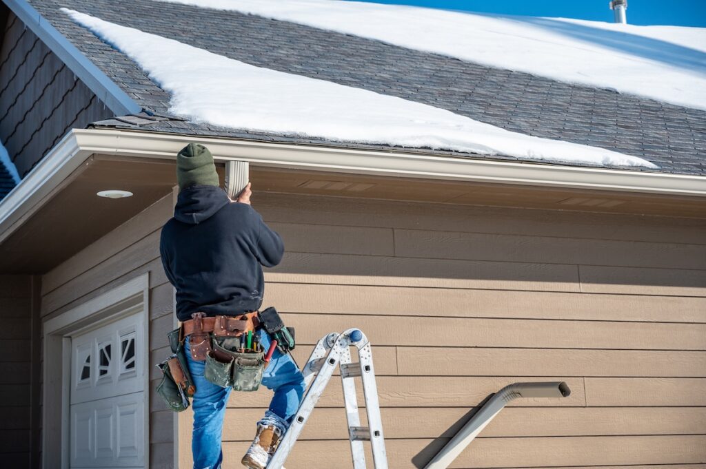 Contractor installing gutters on a residential building
