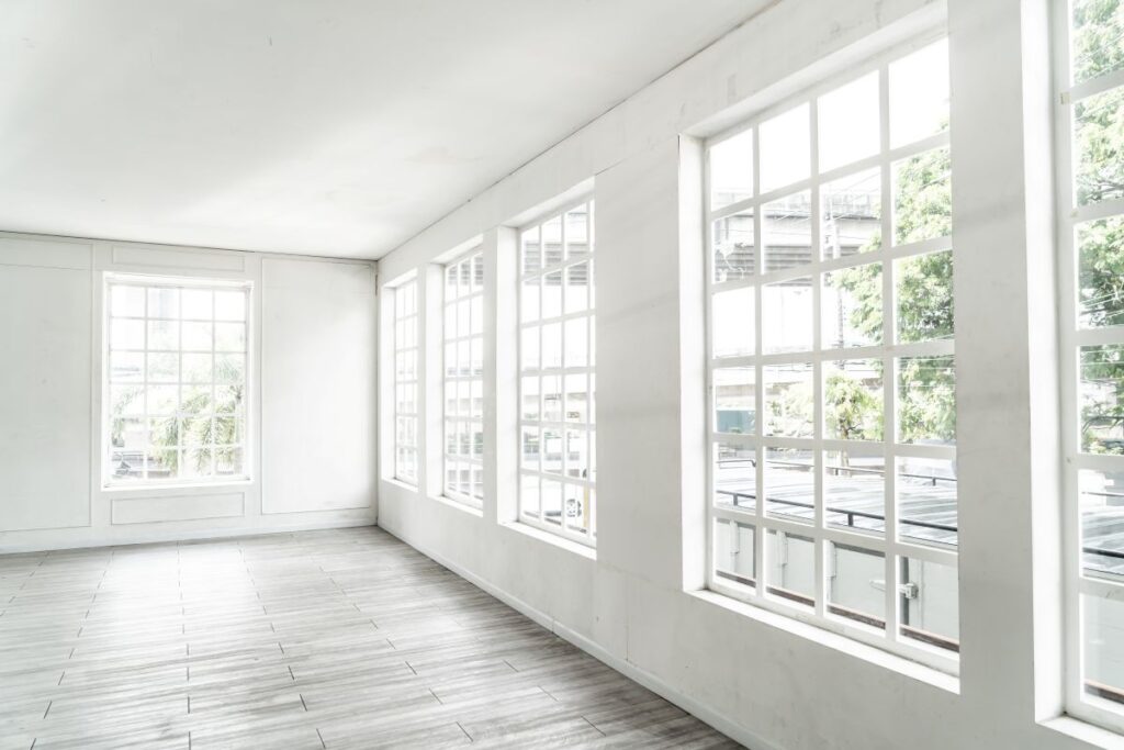 white and bright room with large white windows showing greenery